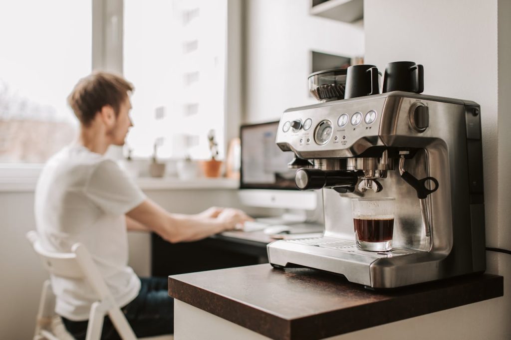 Male freelancer work on desktop computer near coffee machine